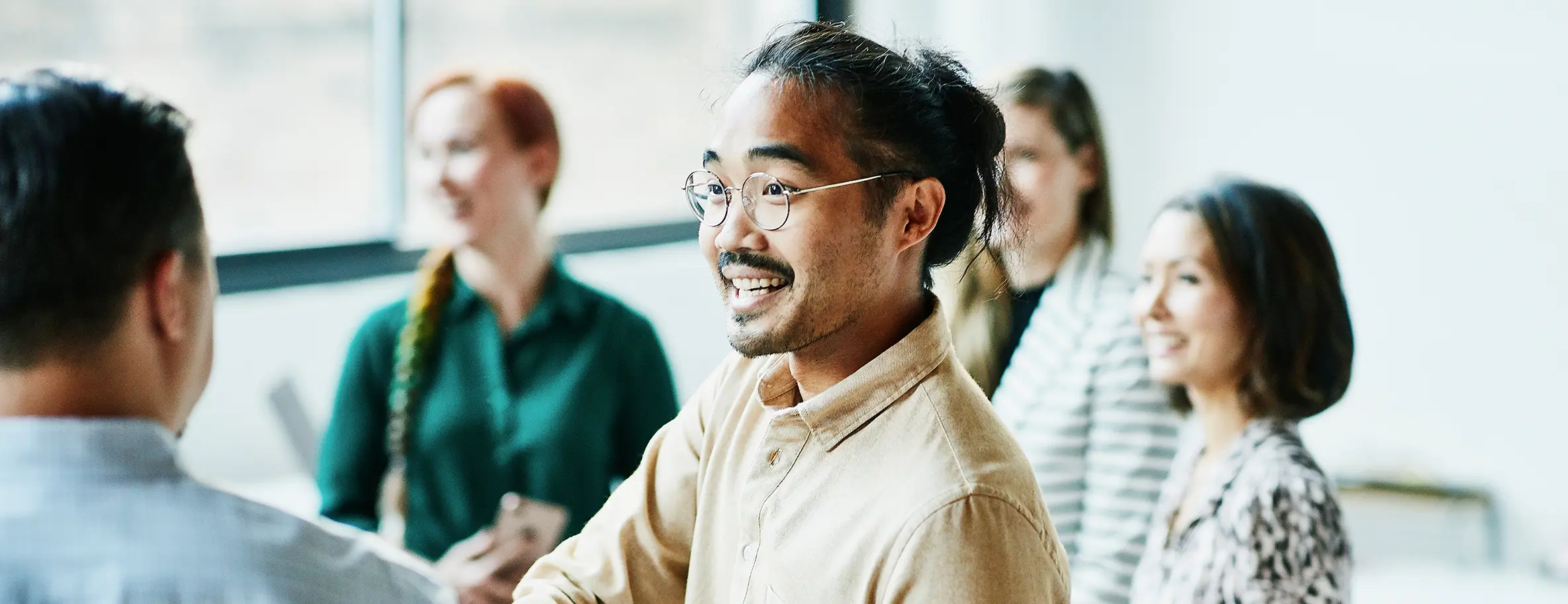 Man in glasses and man bun shaking hands with colleague